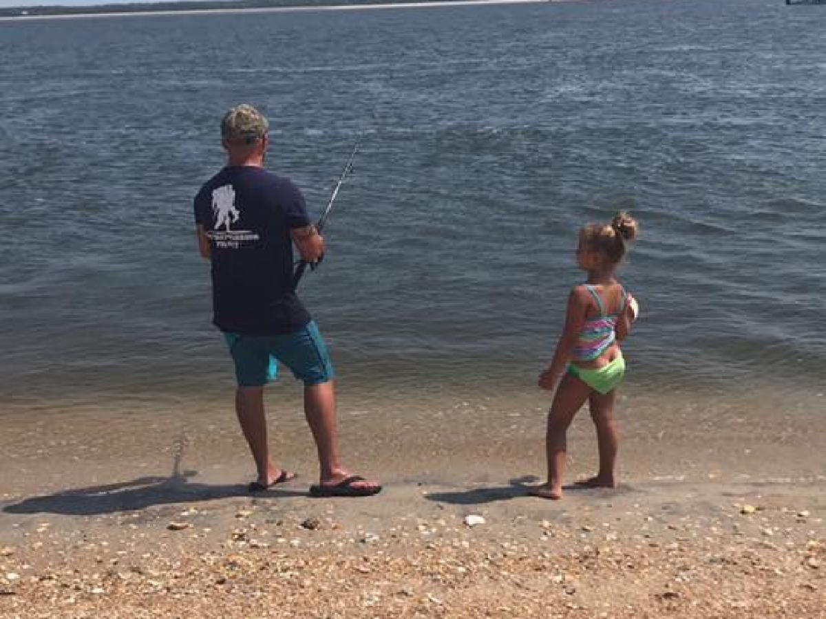man and daughter fishing on beach
