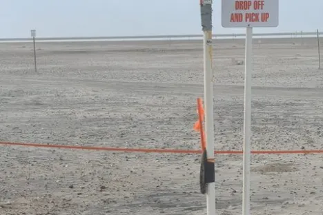 Sign on sandy beach for shuttle drop-off and pick-up.