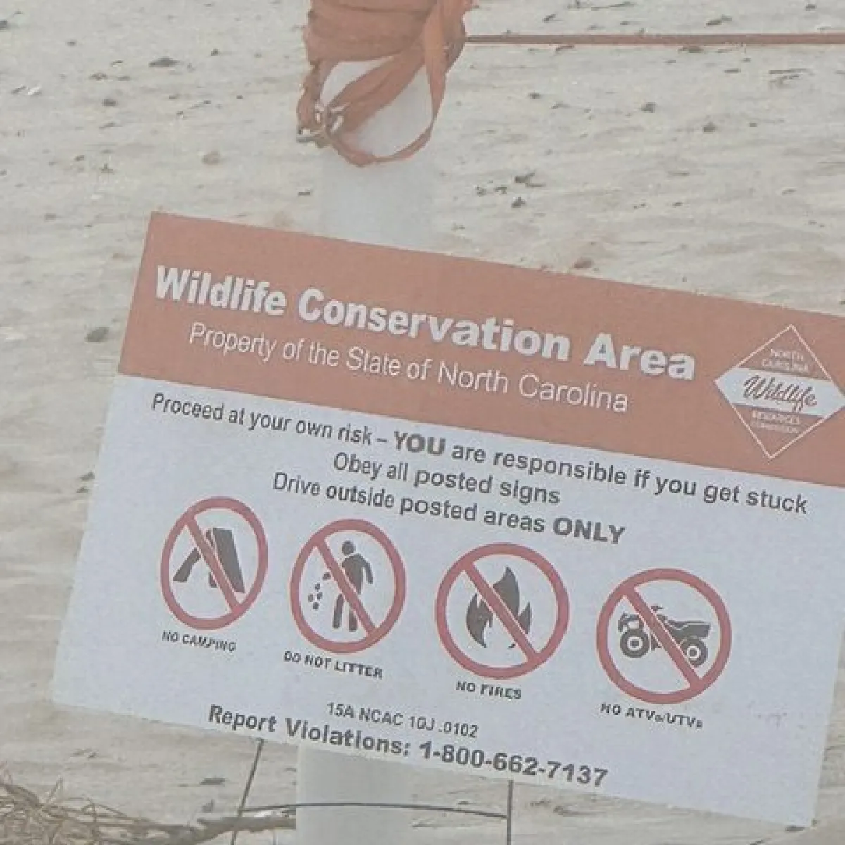 Sign warning about Wildlife Conservation Area with rules and contact information.